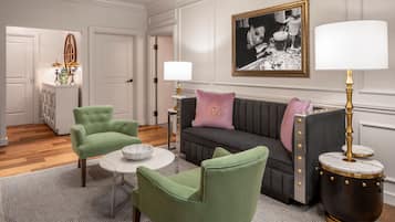 A room with a green sofa, two green armchairs, a round coffee table, and a side table with a lamp.