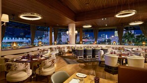 A restaurant with a view of a city skyline at night, featuring wooden ceiling, round tables, and modern lighting. - The Vanderpump Las Vegas Hotel Casino - A Caesars Rewards Destination (Las Vegas)