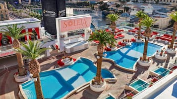 A rooftop pool area with multiple swimming pools, palm trees, and a large sign for 'LEIA LAS VEGAS'.
