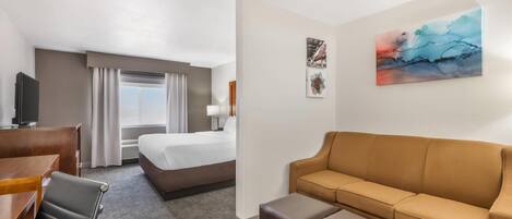 A hotel room with a bed, a sofa, a desk, and a chair.
