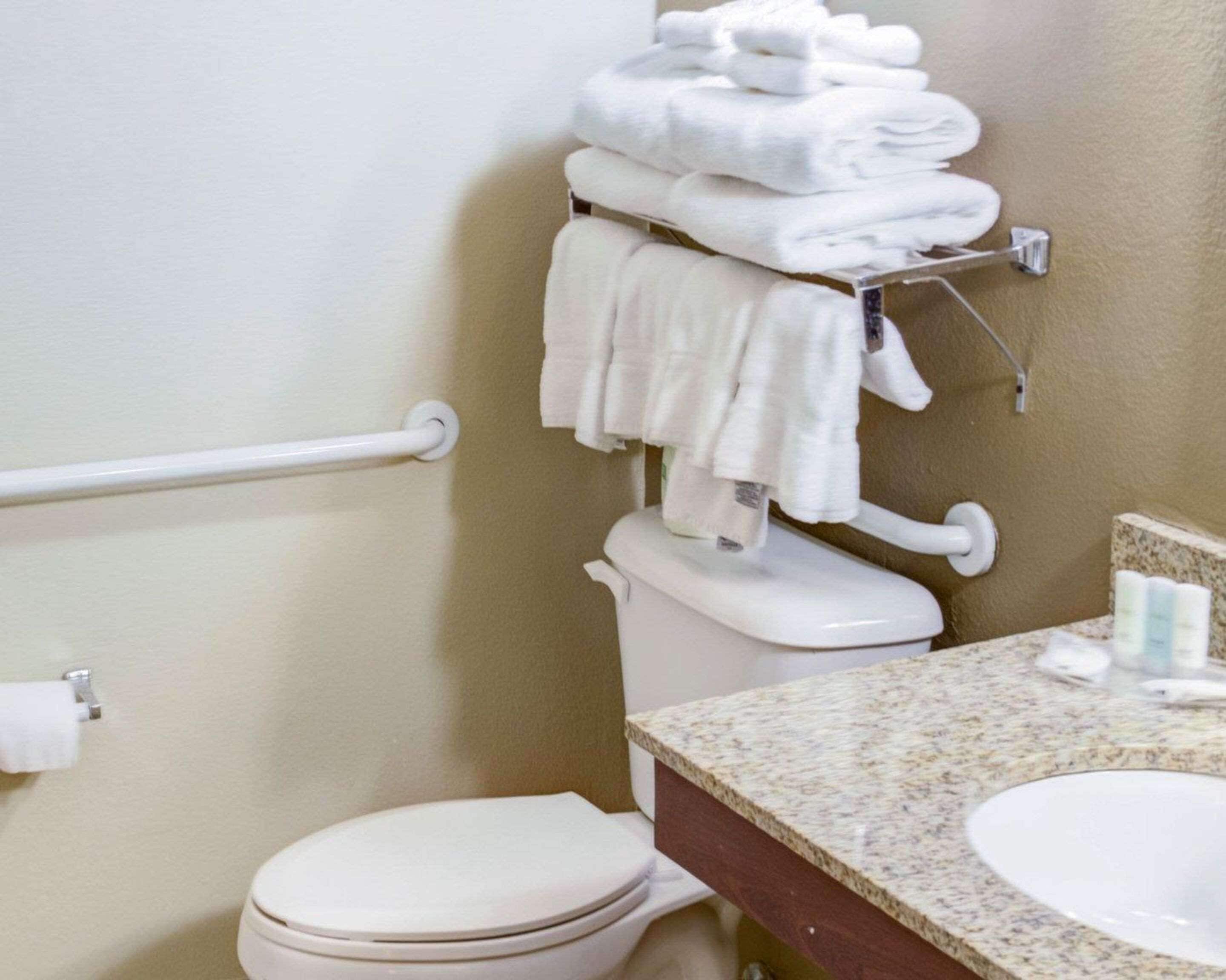 A bathroom with a toilet, a sink, and a towel rack with folded towels.