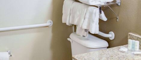 A bathroom with a toilet, a sink, and a towel rack with folded towels.
