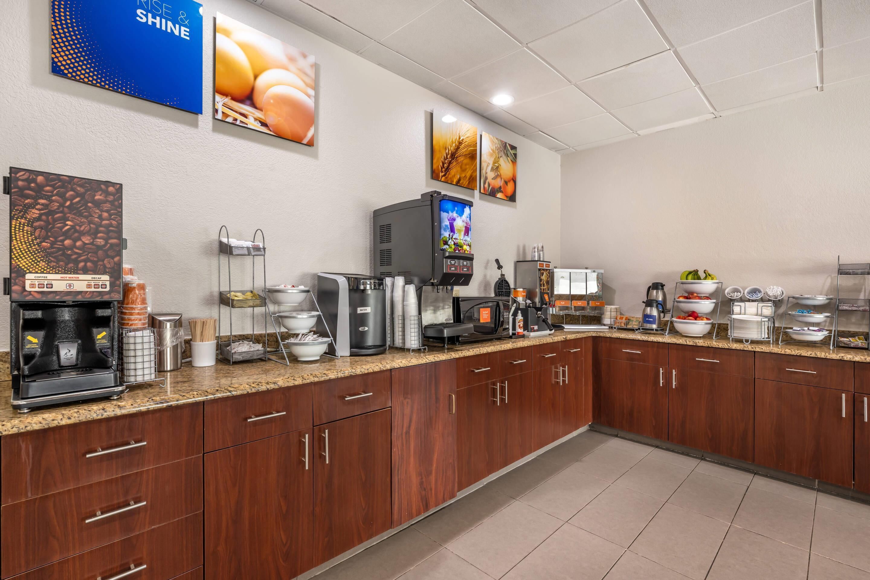 A modern kitchen with a coffee station, a water dispenser, and a food display.