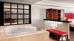 Ein modernes Badezimmer mit einer großen Badewanne, einer Sitzbank, einem Holzschrank mit aufgehängter Kleidung und einem roten Kopfteil.