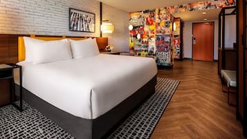 Une chambre d’hôtel avec un grand lit, un mur en briques, une fresque colorée et un plancher en bois.