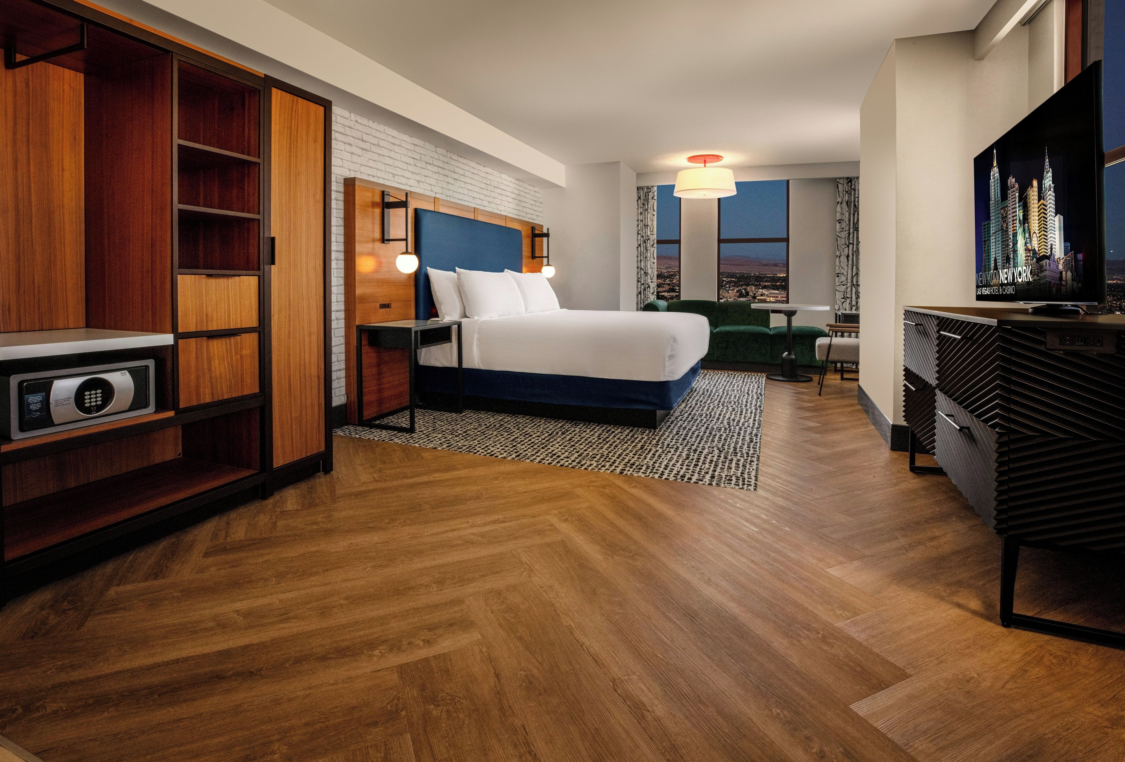 Ein Hotelzimmer mit Bett, Fernseher, Schreibtisch und Blick auf die Stadt.