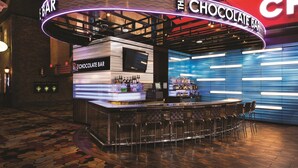 Eine Bar mit einer Theke, Barhocker und einem Neonlichtschild mit der Aufschrift "The Chocolate Bar".