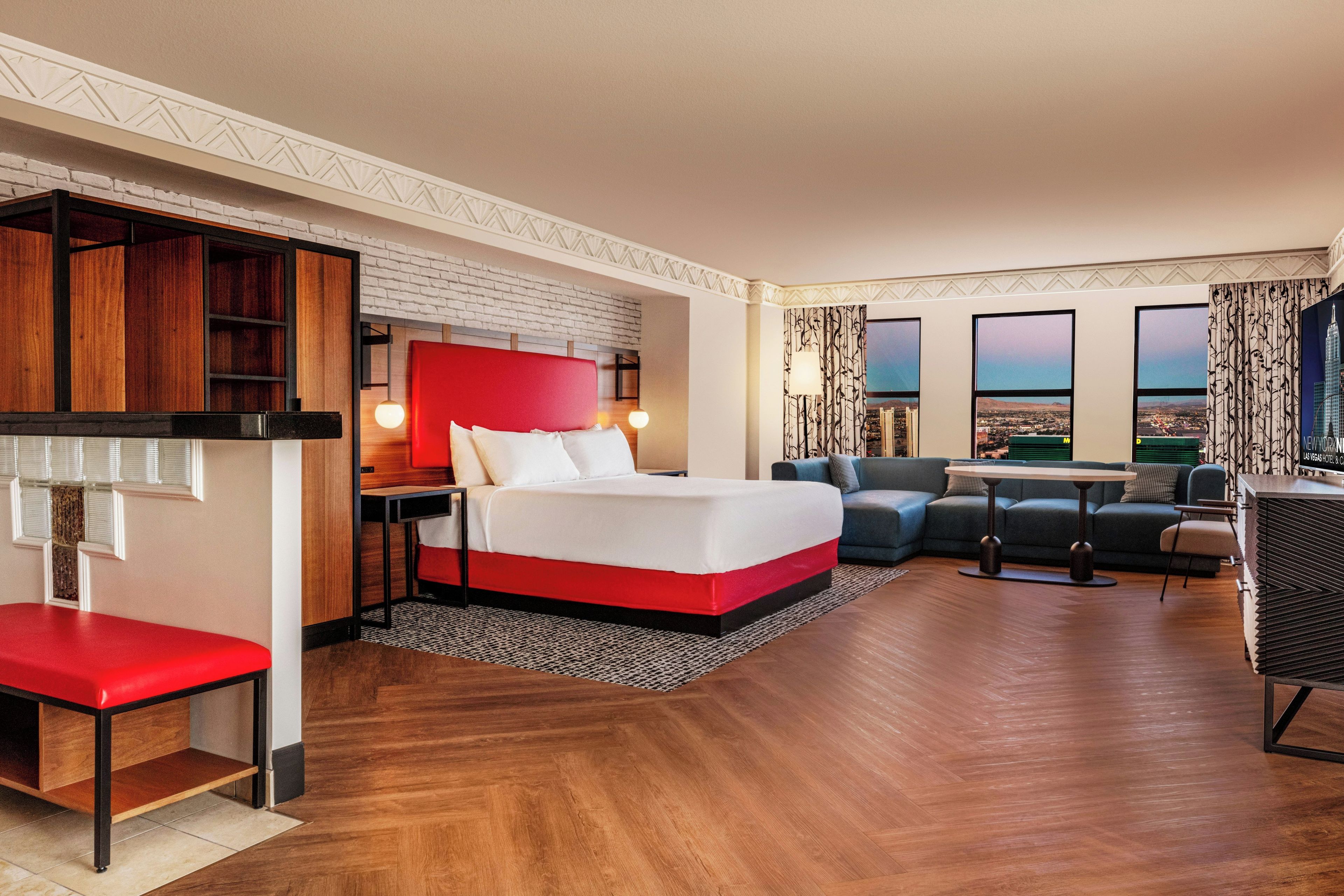 Een hotelkamer met een bed, een sofa, een bureau en uitzicht op de stad.