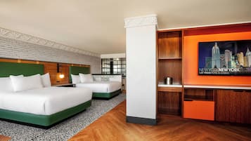 A hotel room with two beds, a desk, a minibar, and a cityscape poster.