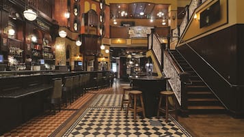 Un bar con piso a cuadros, mostrador de madera y taburetes.