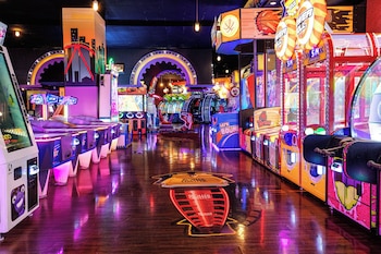 A restaurant with a unique ceiling mural depicting a natural landscape, wooden tables and chairs, and a carpeted floor. at New York-New York Hotel & Casino