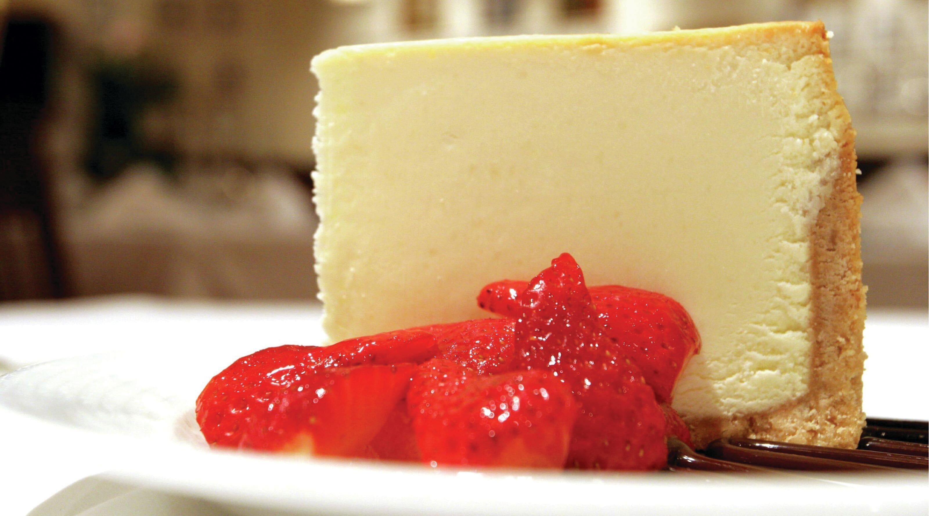 A slice of cheesecake with strawberries on a white plate.