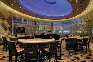 Un moderno vestíbulo de hotel con una zona de bar circular, asientos c ómodos y una gran pantalla digital.