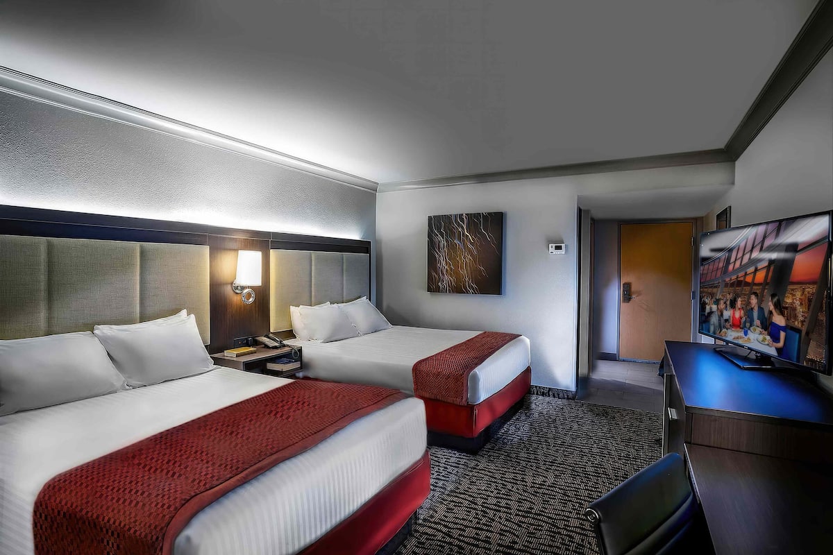 Habitación de hotel con dos camas, televisión y un cuadro en la pared.