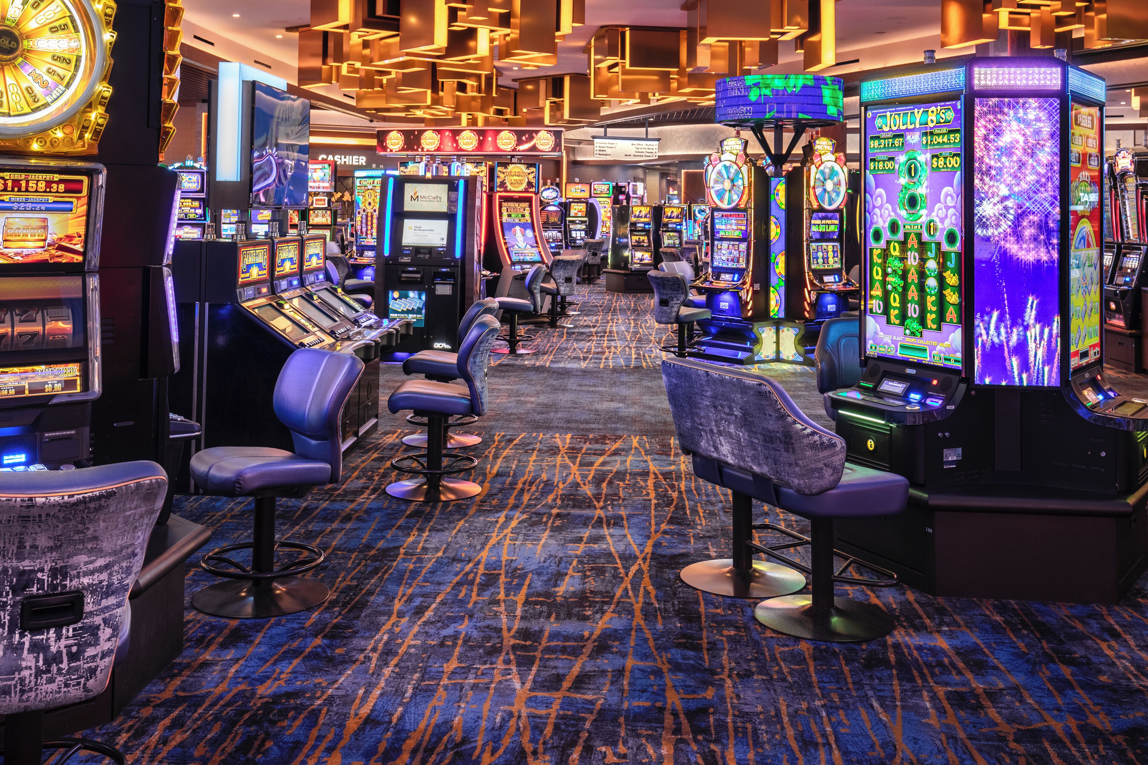 A casino floor with multiple slot machines, bar stools, and a carpeted floor.