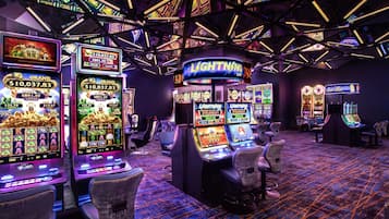 Experience the excitement of gaming and socializing in this vibrant casino setting, featuring slot machines and gaming tables.