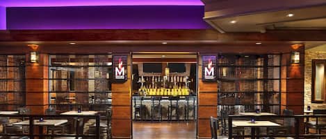 A restaurant with a bar area, wooden furniture, and a patterned carpet.