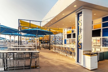 A bar area with a neon-lit floor, bar stools, and a large screen displaying a game. at The STRAT Hotel, Casino & Tower