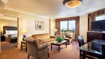 Habitación de hotel con cama, sofá, mesa de centro, televisor y vista a la ciudad.