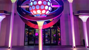 Un bâtiment sur lequel on peut lire l’inscription « ATOMIC GOLF », avec une grande sculpture sphérique illuminée devant.