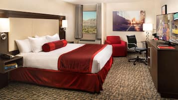 Ein Hotelzimmer mit einem großen Bett, einem Schreibtisch, einem Stuhl und einem Fernseher.