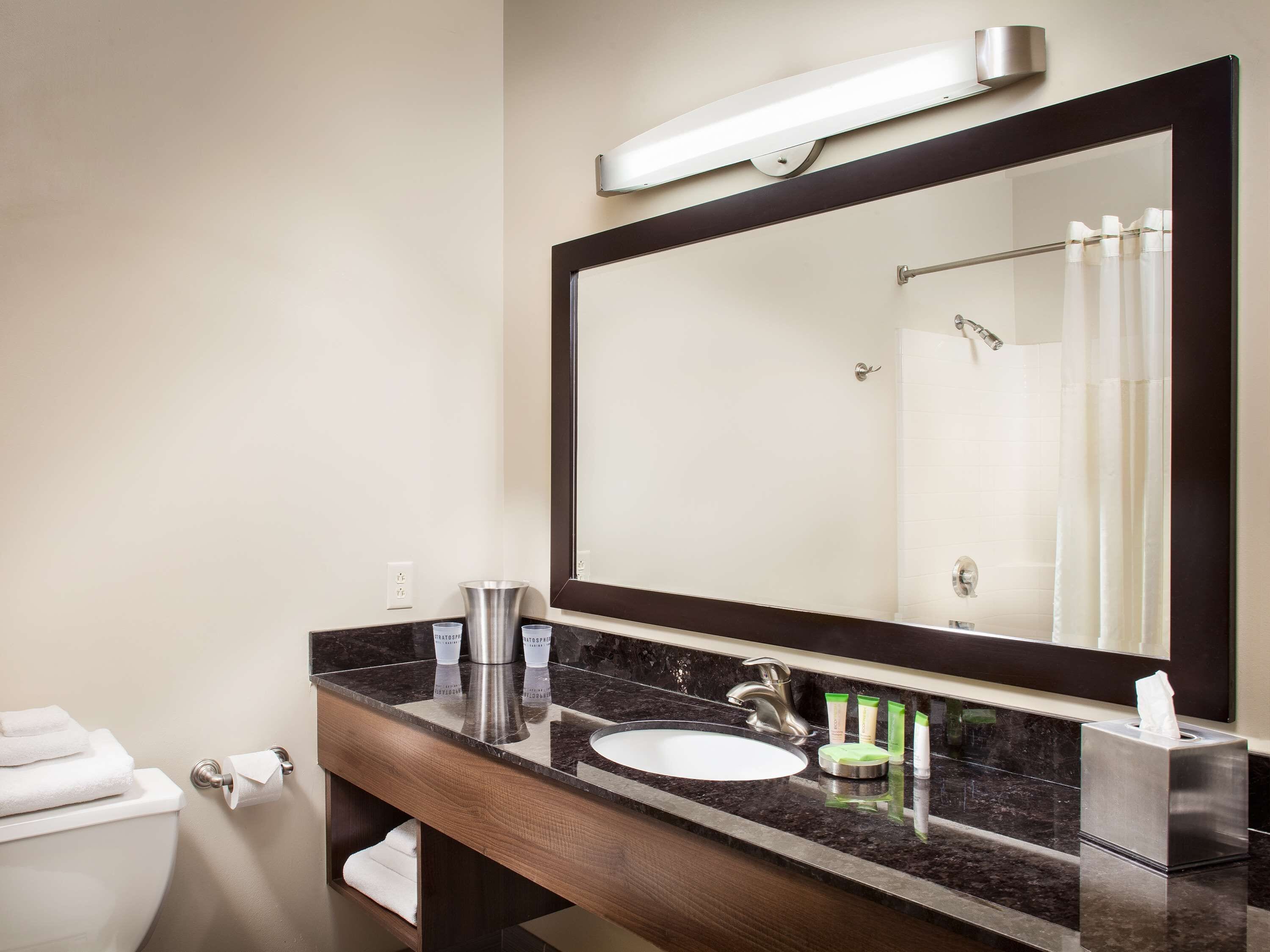 A modern bathroom with a large mirror, a sink, and a toilet.