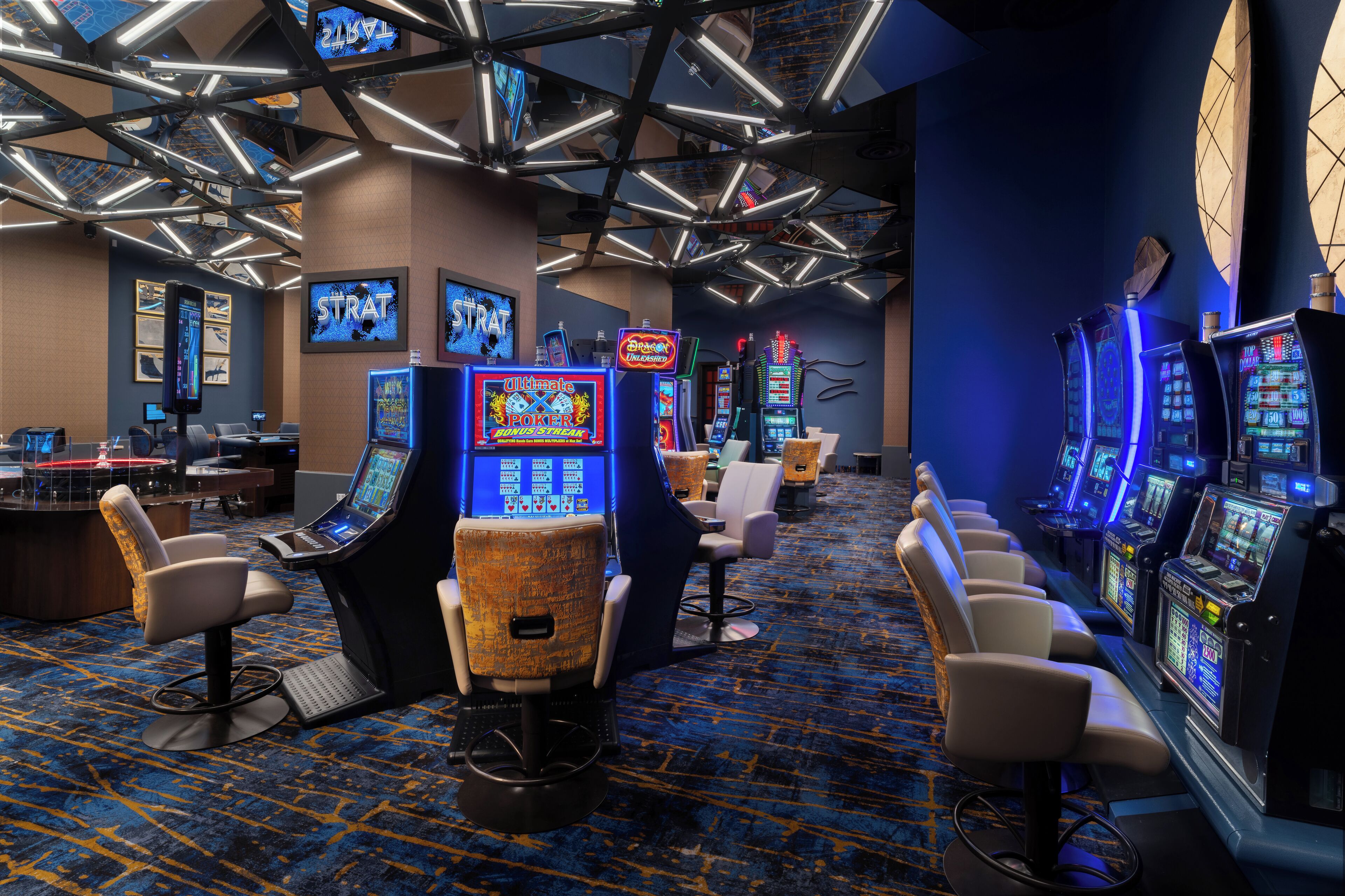 A casino with multiple slot machines, gaming tables, and comfortable seating areas.