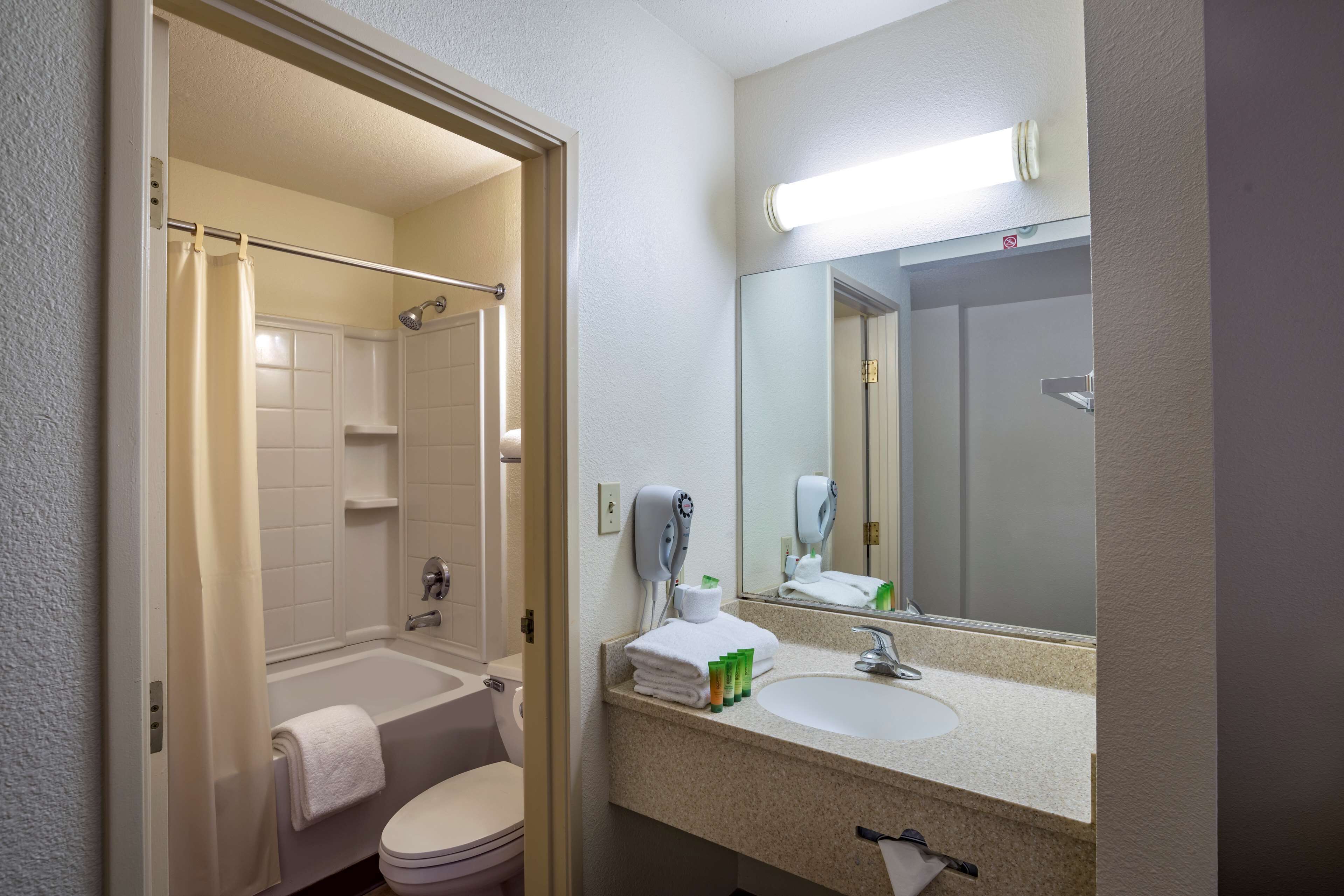 A bathroom with a shower, toilet, sink, and a mirror.