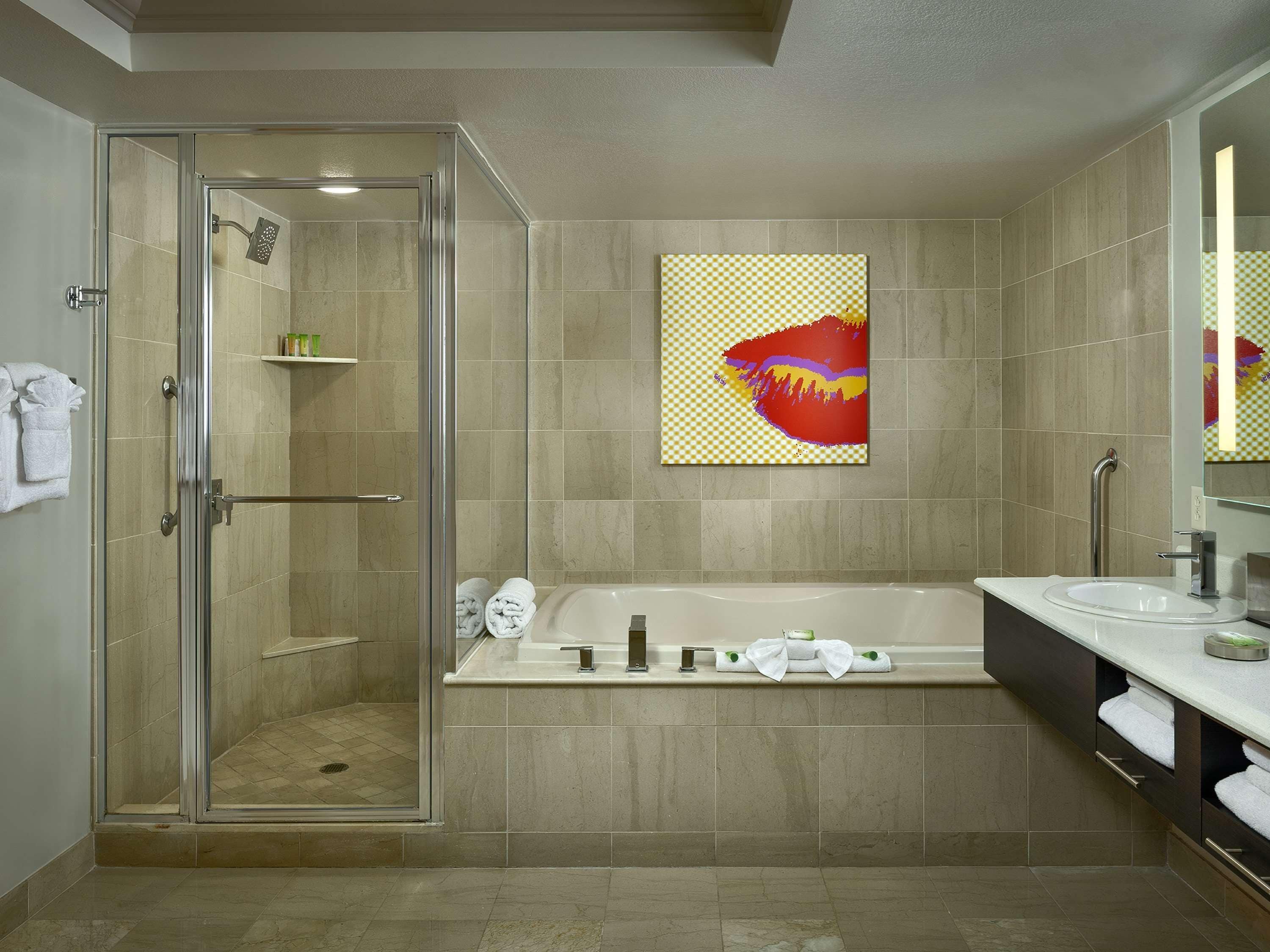 Un baño moderno con ducha de vidrio, bañera independiente y un espejo grande.