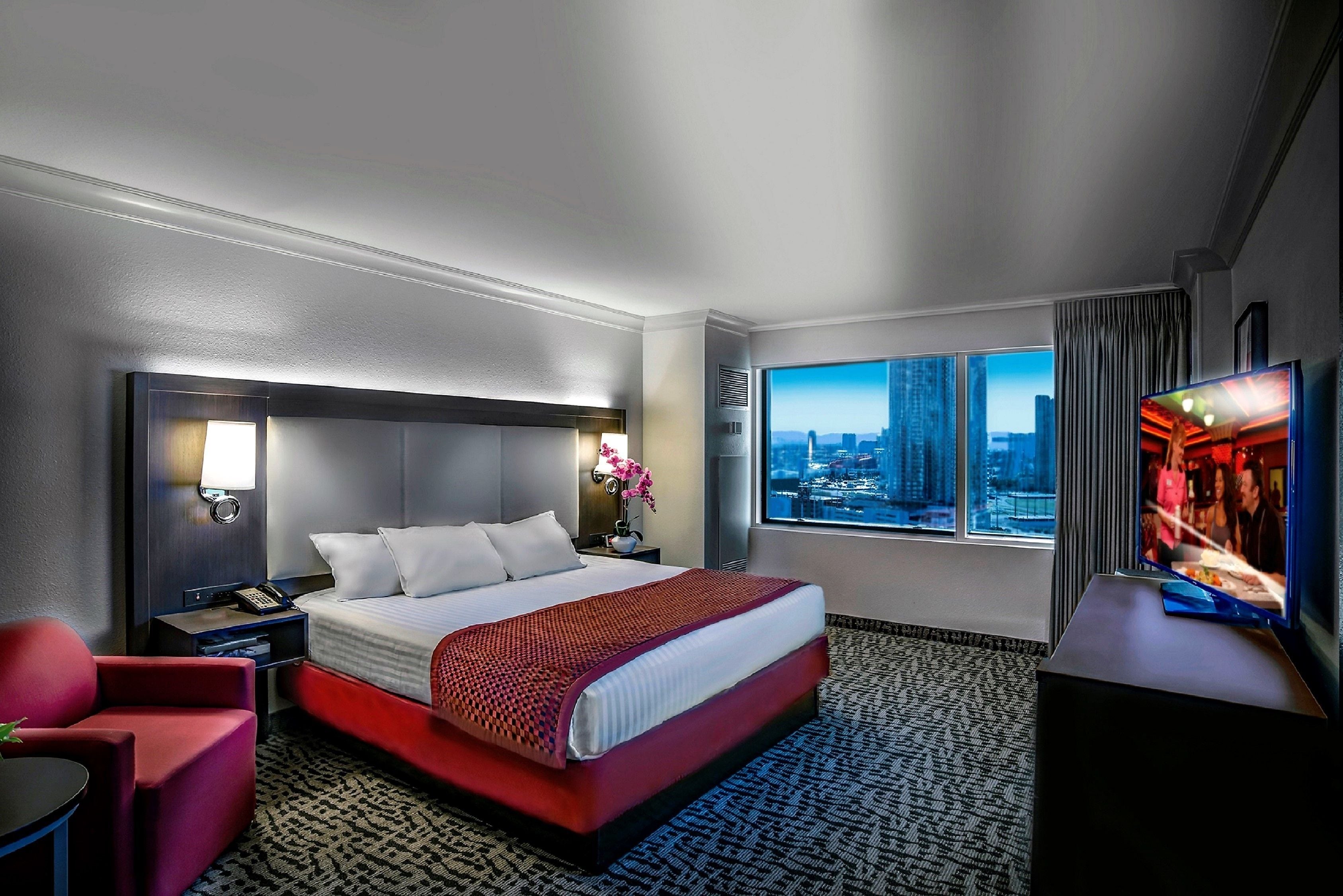 Une chambre d’hôtel avec un grand lit, une télévision, un bureau, une chaise et une vue sur la ville.