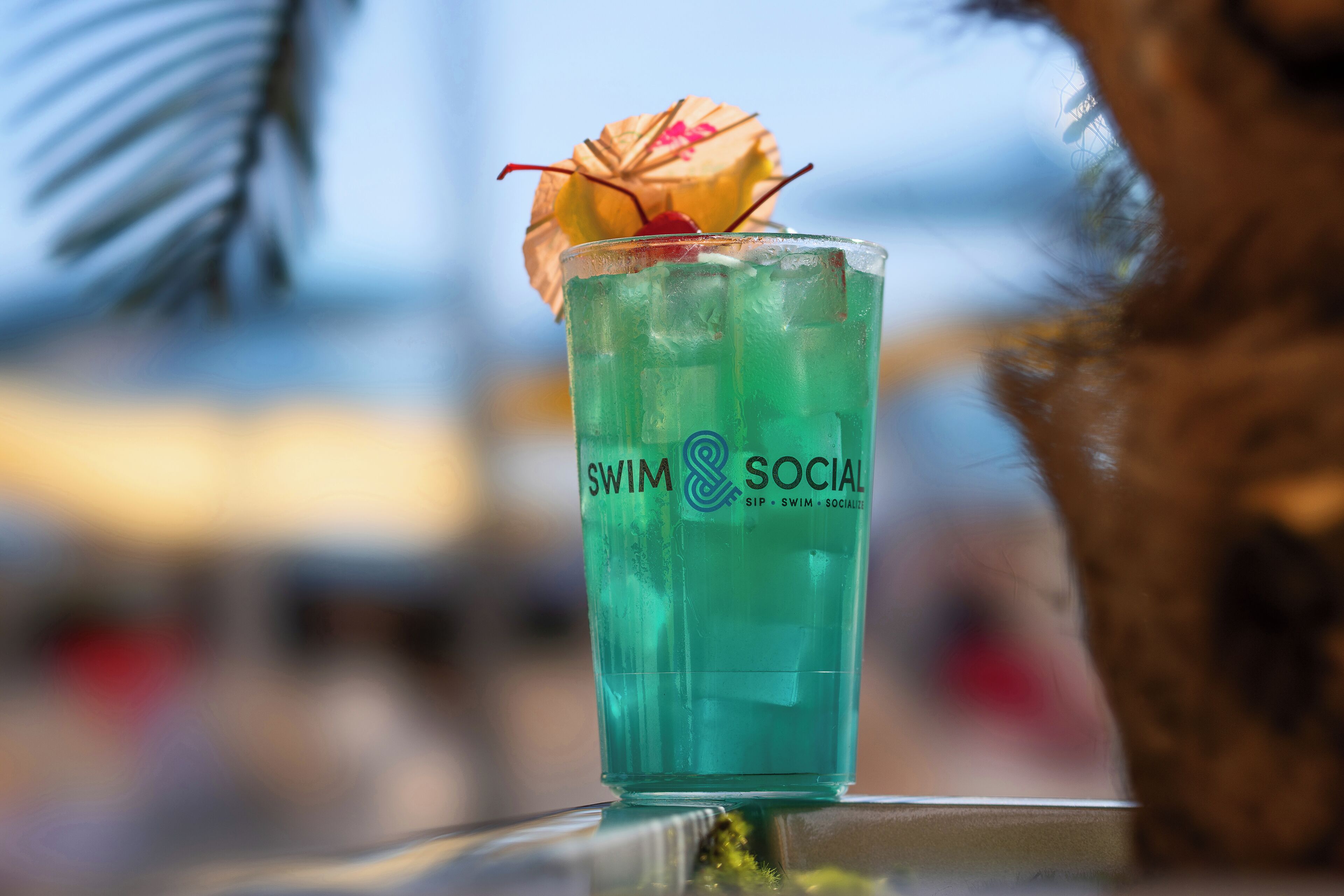 A glass with a tropical drink, a straw, and a decorative umbrella.