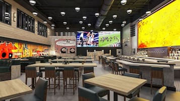 A modern bar area with multiple seating options, including tables and booths, and a large screen displaying sports events.