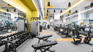Un gimnasio con varios equipos de ejercicio, como cintas de correr, máquinas de pesas y mancuernas.