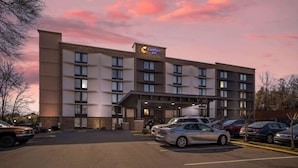 Modernilla designilla varustettu Comfort Inn -hotelli, jossa on useita autopaikkoja, kirkas taivas vaaleanpunaisine pilvineen ja hyvin valaistu sisäänkäynti.