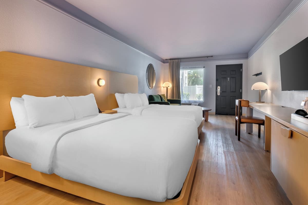 Habitació d'hotel amb dos llits, una taula de treball, una cadira i una televisió.
