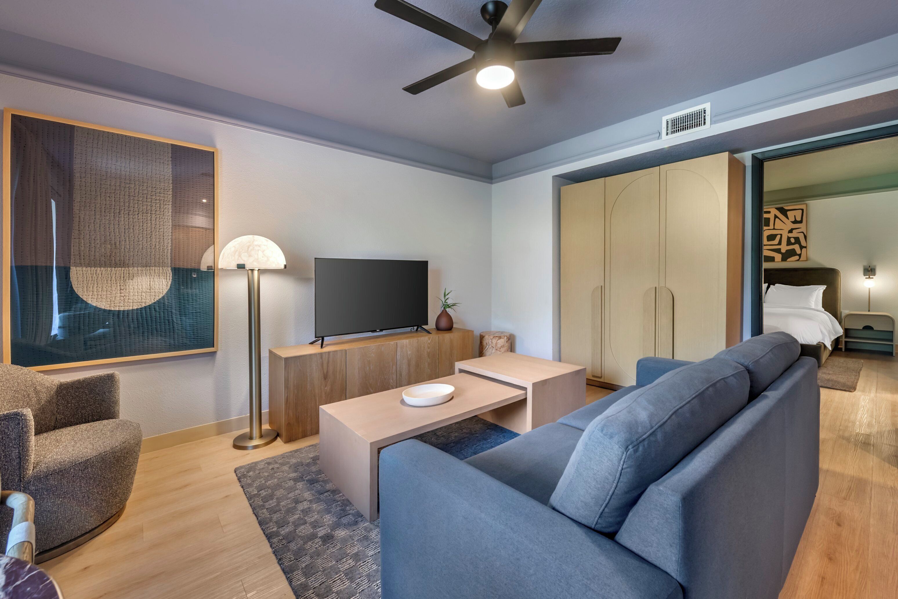 Una sala de estar moderna con un sofá, televisor y ventilador de techo.