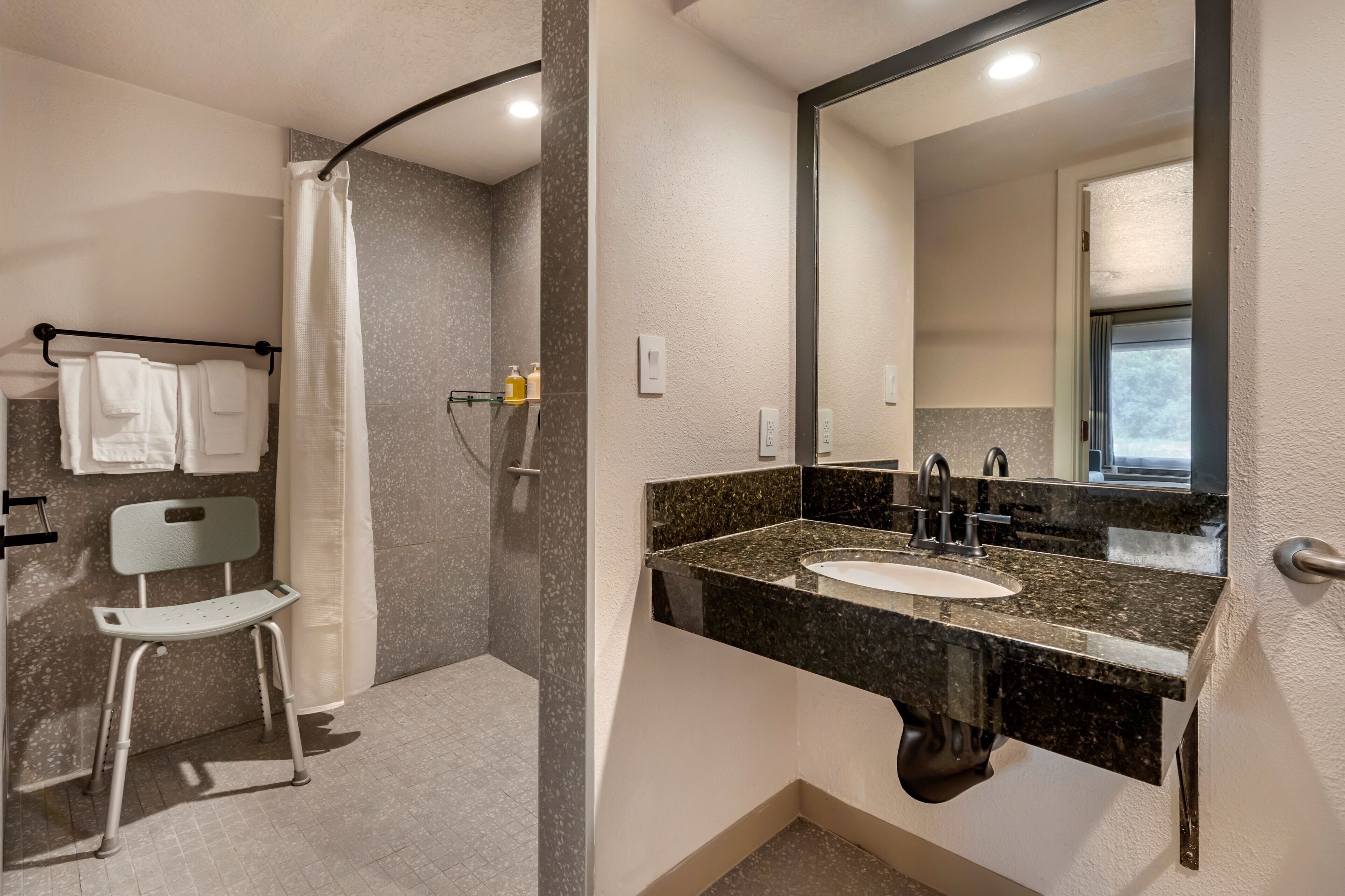 Een moderne badkamer met een douche, toilet, wastafel en spiegel.