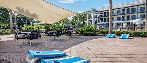 A poolside area with lounge chairs, tables, and umbrellas.