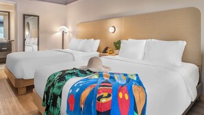 A hotel room with two beds, a large mirror, a bedside lamp, and a colorful blanket. - voco Kissimmee Orlando by IHG (Kissimmee)