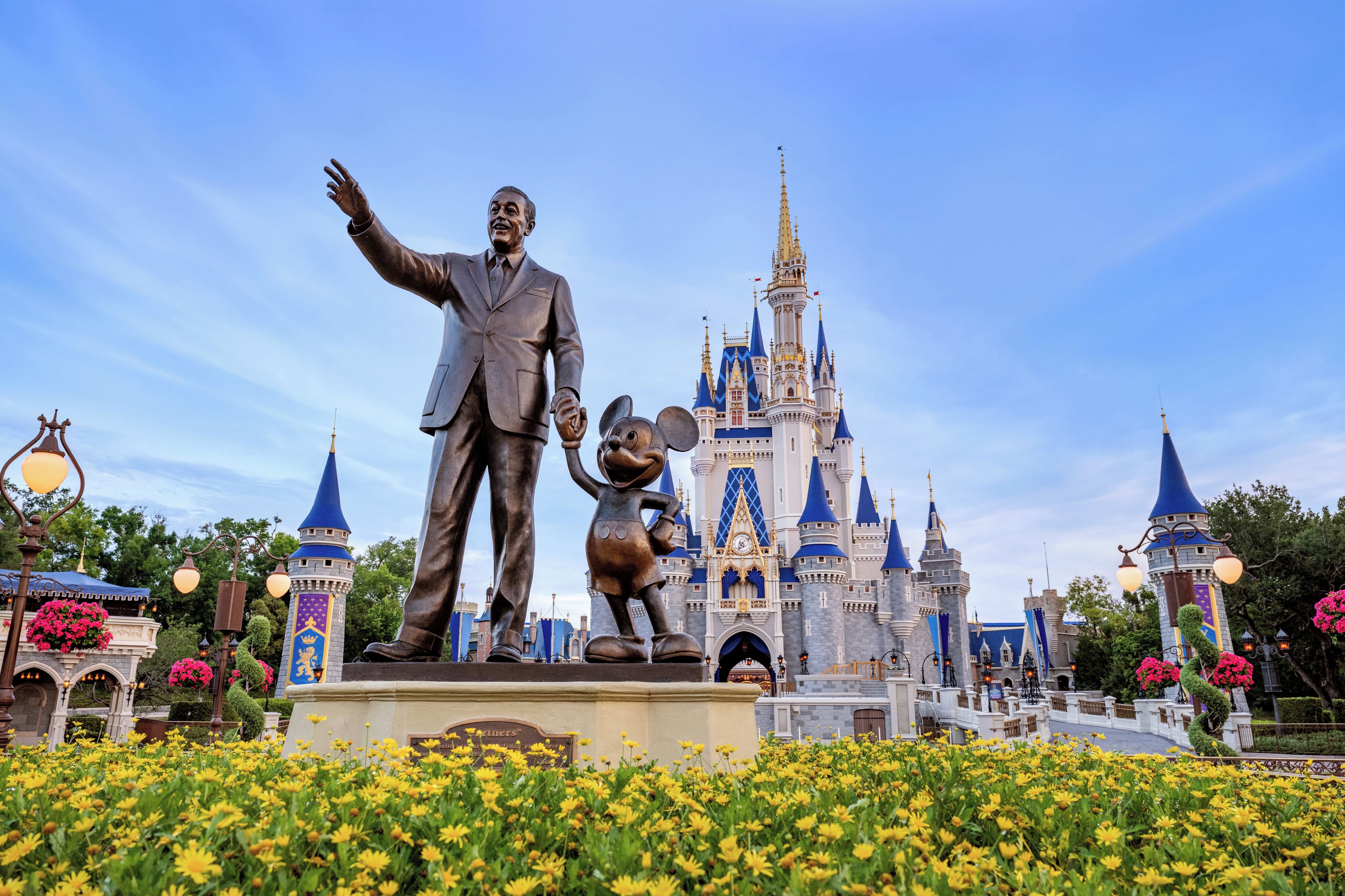 Une statue représentant un homme et une souris, placée devant un château.