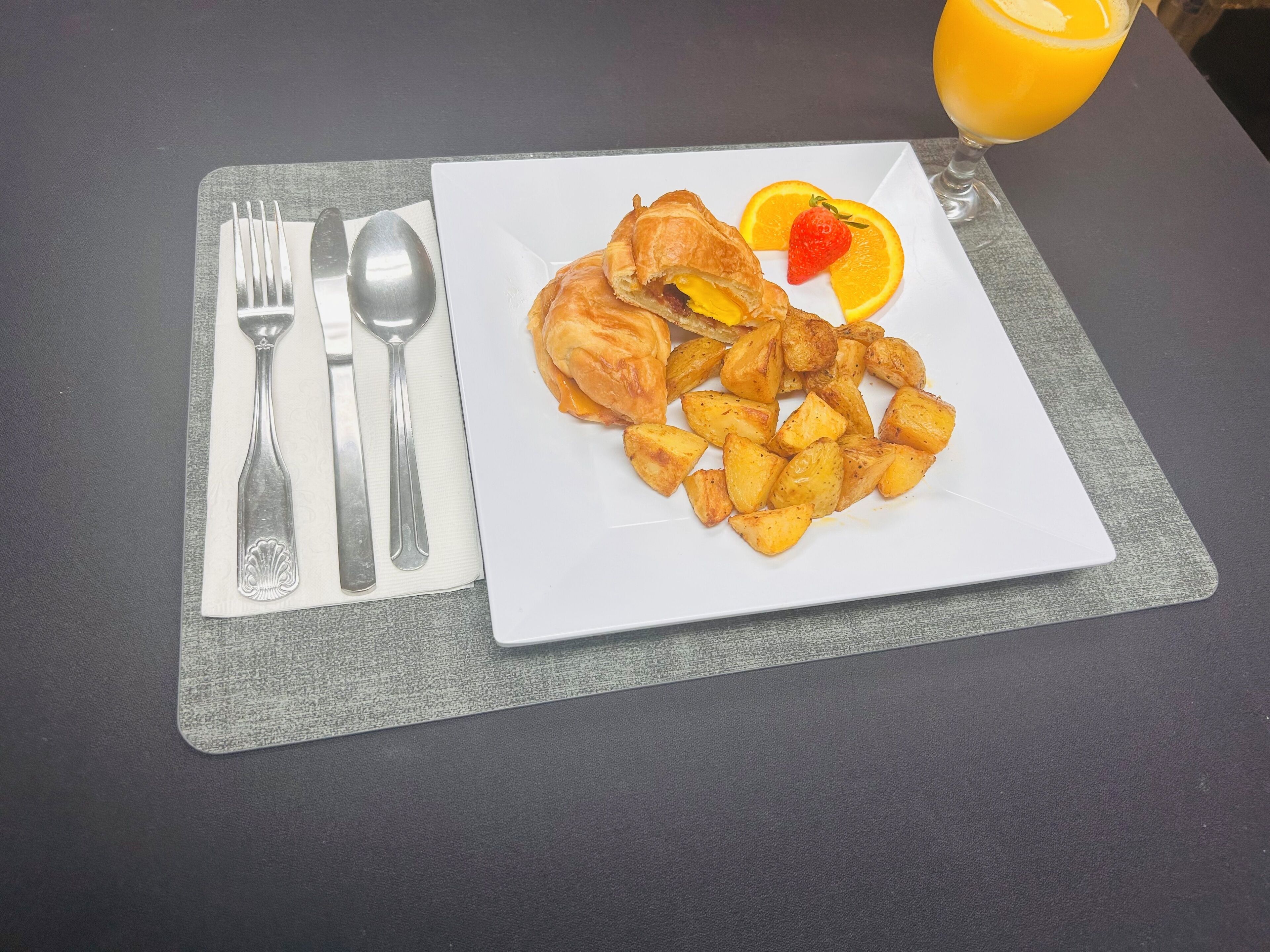 Un plato con comida y un vaso de jugo de naranja sobre una mesa.