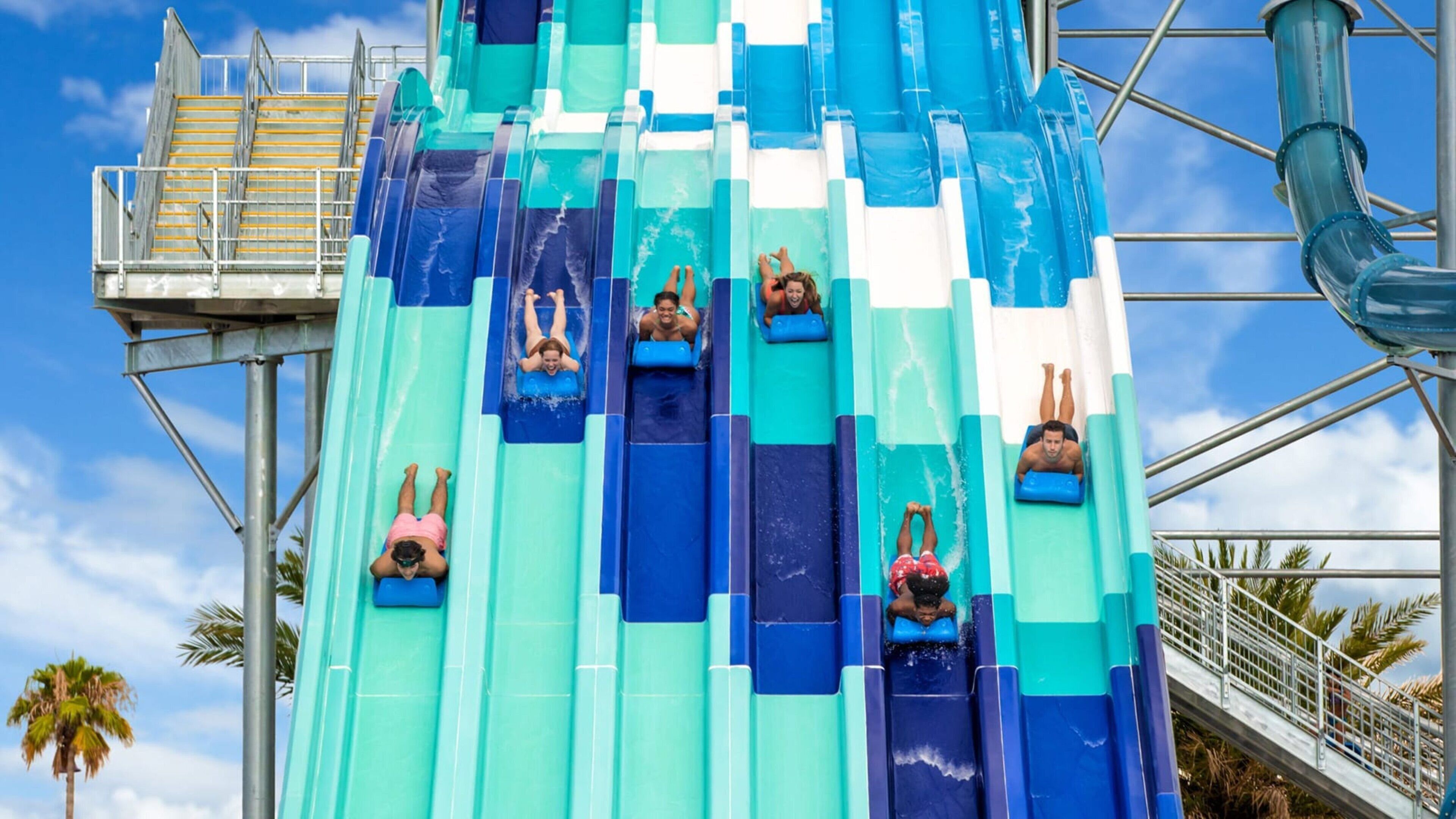 A water slide with multiple lanes and a metal staircase on the left.