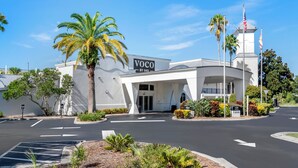 Un edificio moderno con un cartello che riporta "Voco by IHG" e un'asta con la bandiera americana.