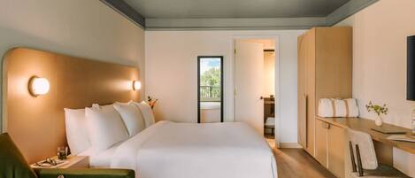 Habitación de hotel moderna con una cama grande, un sofá verde, un escritorio con una silla y vistas al exterior.