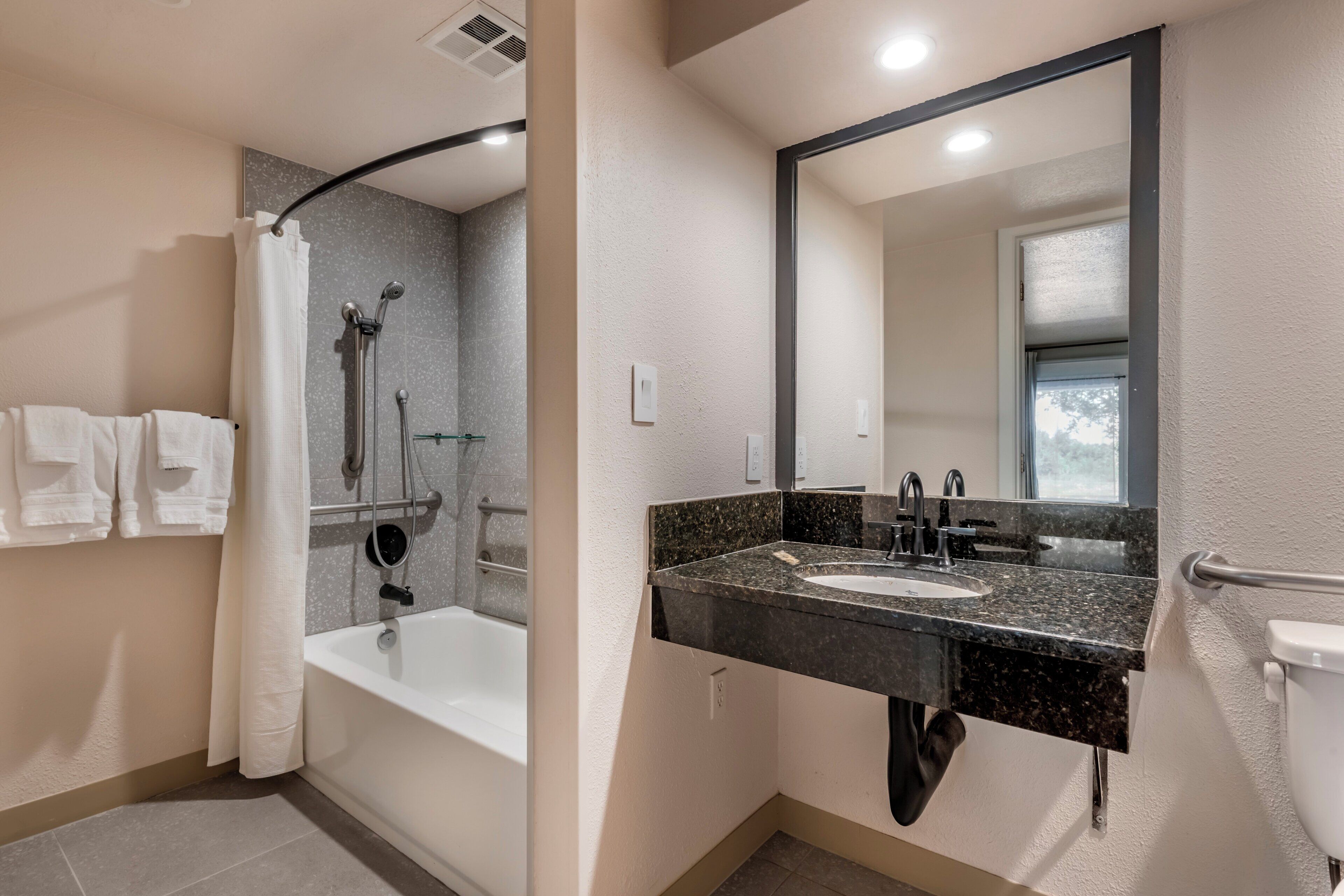 A modern bathroom with a bathtub, a sink, and a large mirror.