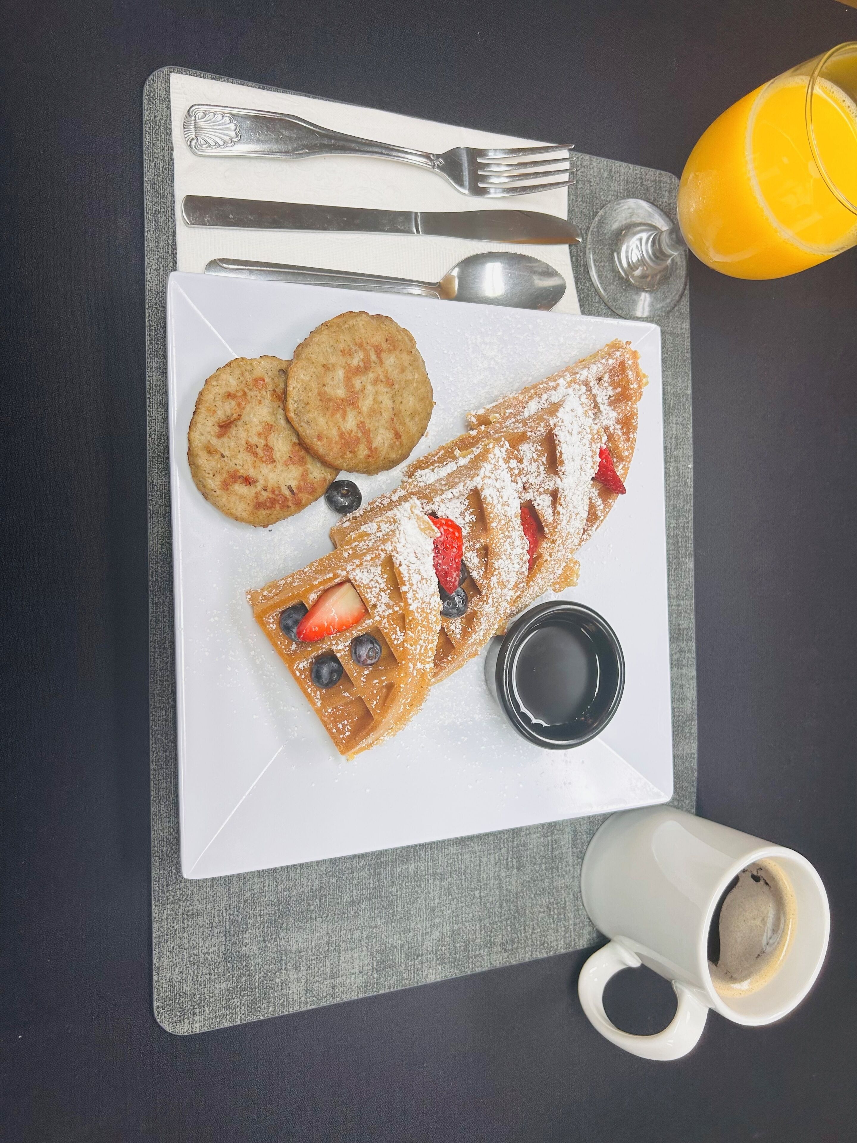 A breakfast tray with waffles, cookies, and a cup of coffee on a table.