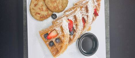 A breakfast tray with waffles, cookies, and a cup of coffee on a table.