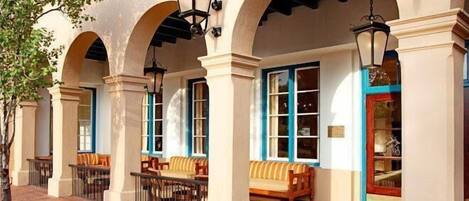 Un hotel con zona de estar al aire libre techada, columnas y faroles colgantes.
