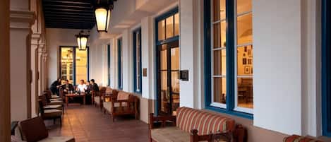 A corridor with seating, tables, and a warm-lit interior.