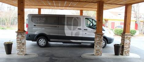 A covered parking area with a van displaying "I LOVE THIS COUNTRY" and a website address.